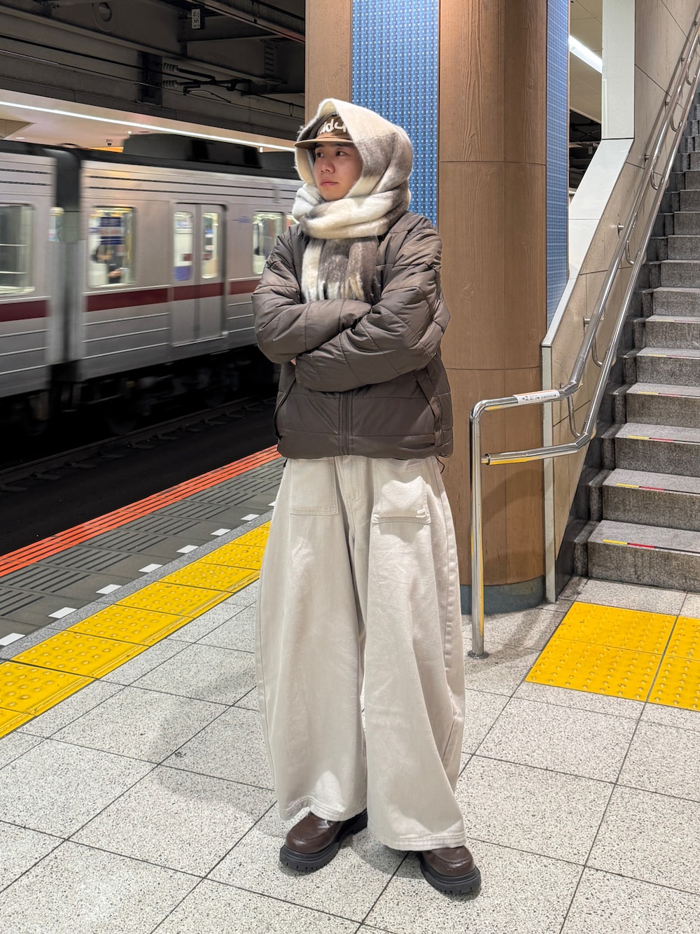 ブラウン系のナイロンジャケット、ベージュ系のパンツ、ブラウン系のローファーを着用したメンズの秋コーディネートの1枚目の写真