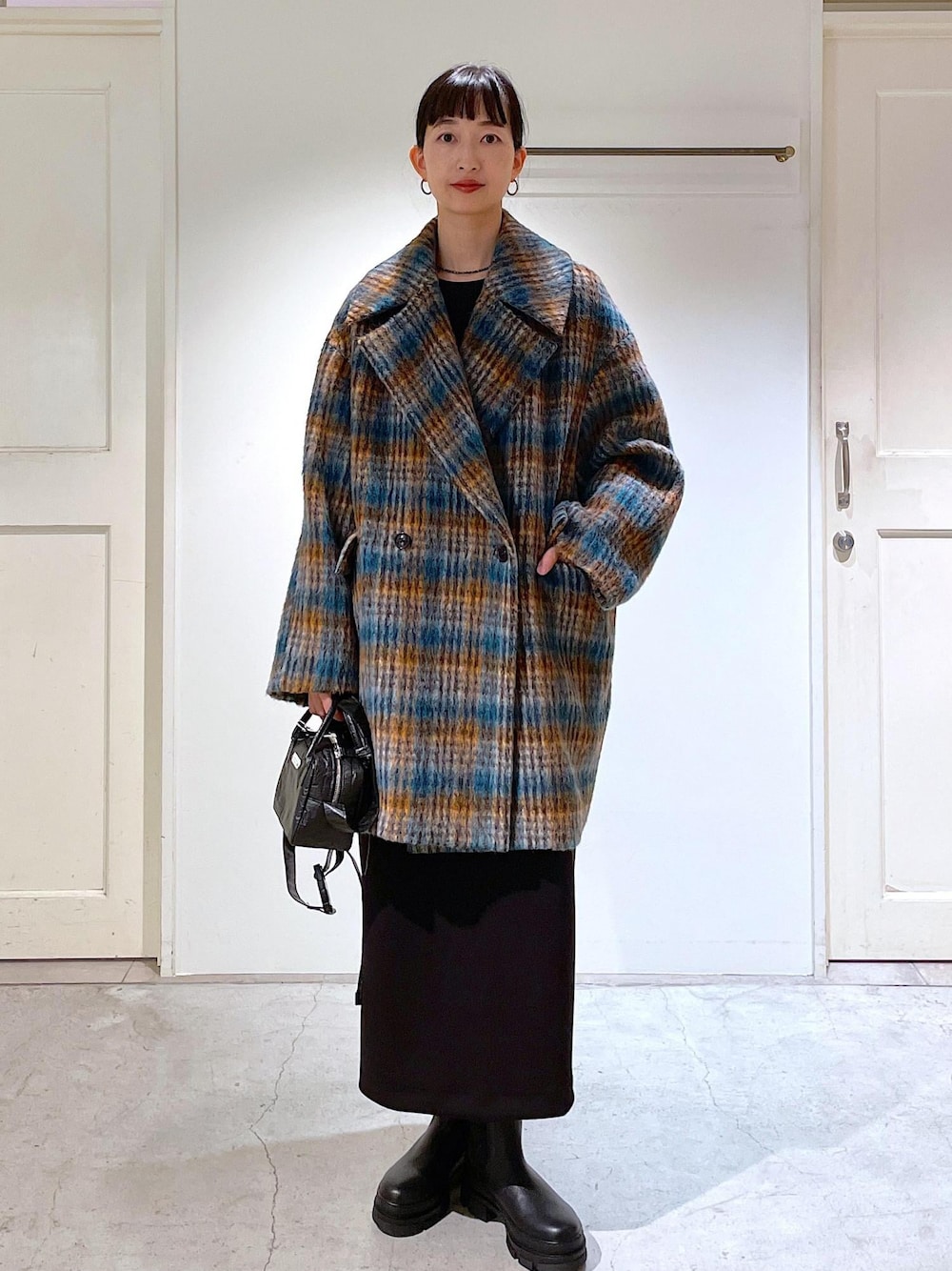 ブルー系のピーコート、ブラック系のブーツ、ブラック系のスカートを着用したレディースの秋コーディネートの1枚目の写真