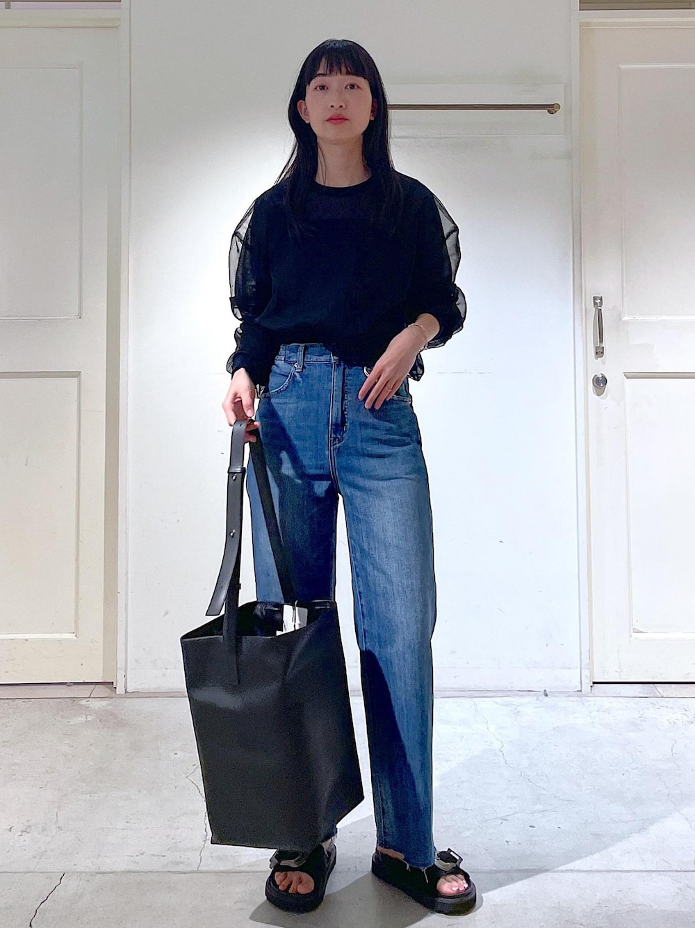 ブラック系のサンダル、ブラック系のトートバッグ、ブラック系のTシャツ/カットソーを着用したレディースの春コーディネートの1枚目の写真