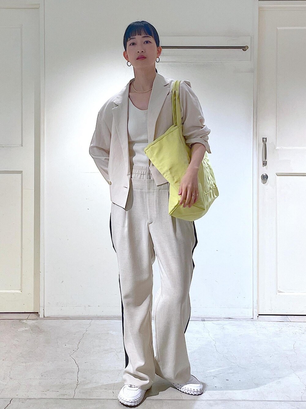 ホワイト系のキャミソール、ホワイト系のテーラードジャケットを着用したレディースの春コーディネートの1枚目の写真