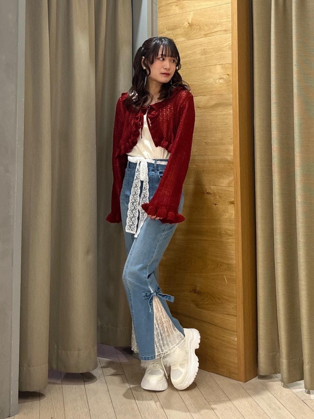 レッド系のカーディガン/ボレロ、ブルー系のデニムパンツ、ホワイト系のスニーカーを着用したレディースの冬コーディネートの1枚目の写真