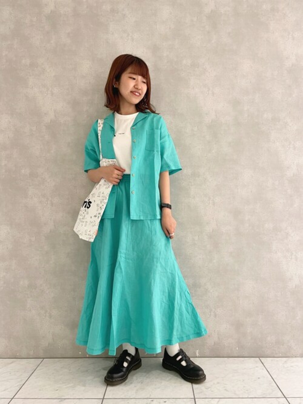 グリーン系のシャツ/ブラウス、グリーン系のスカート、ホワイト系のTシャツ/カットソーを着用したレディースの春コーディネートの1枚目の写真
