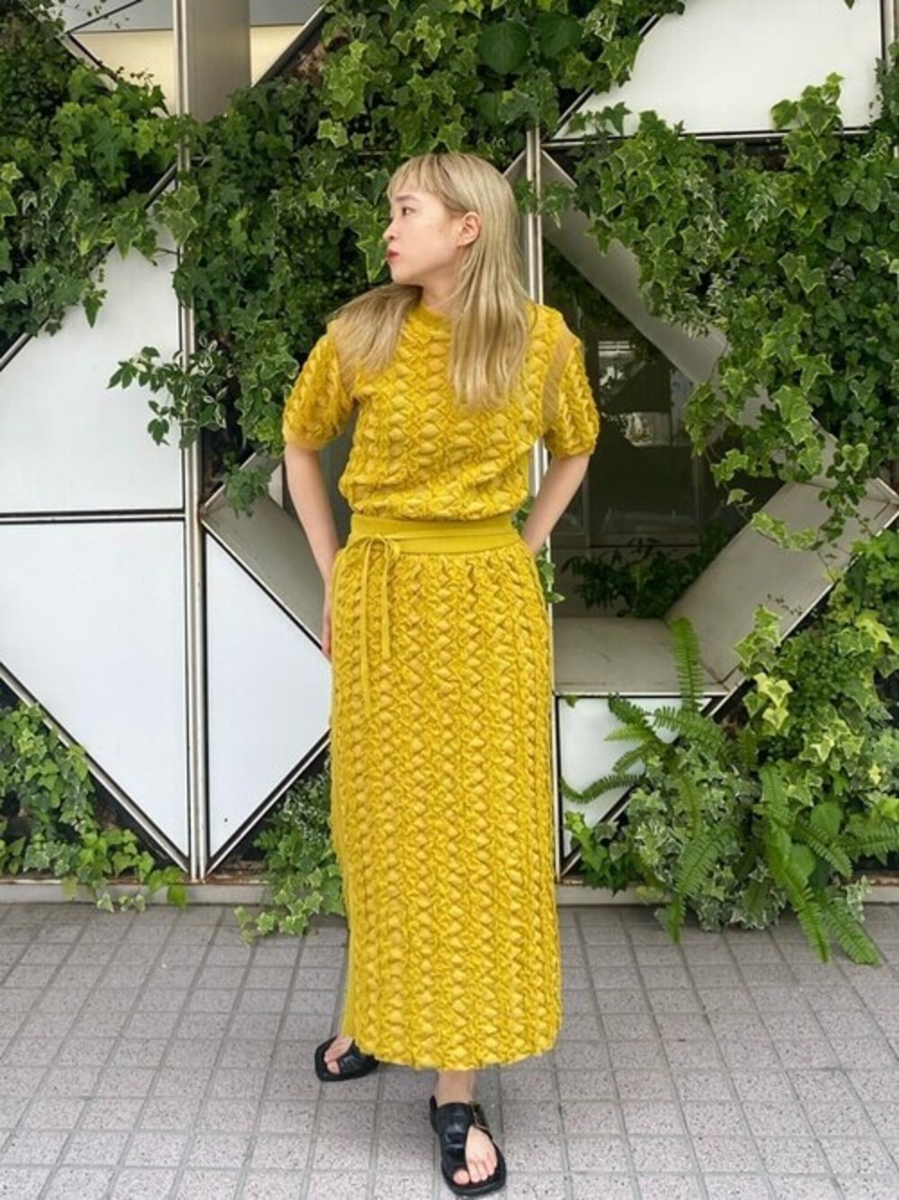 イエロー系のニット/セーター、イエロー系のスカートを着用したレディースの夏コーディネートの1枚目の写真