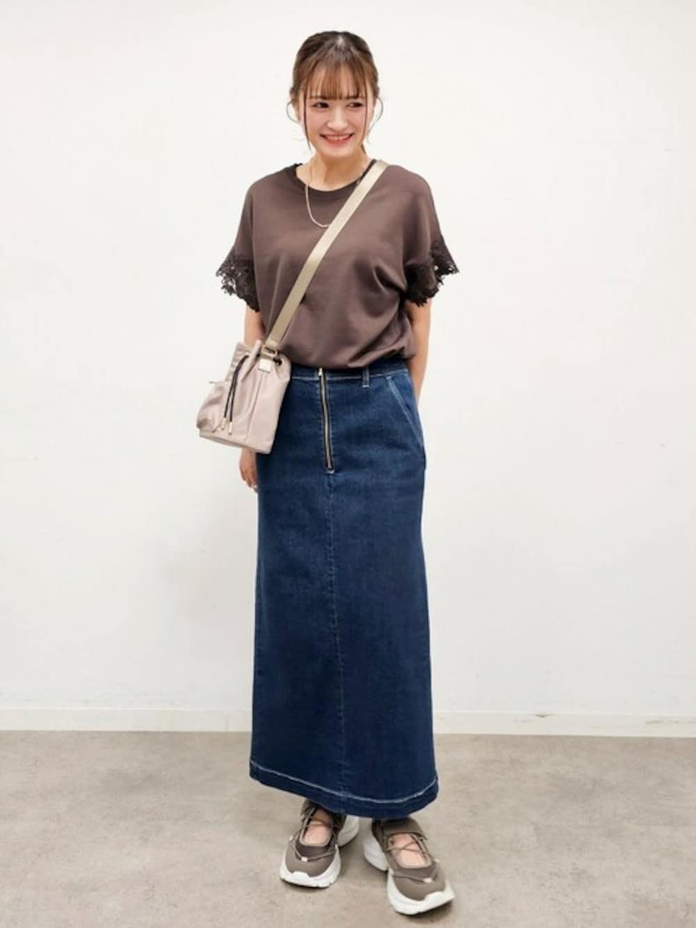 ブラウン系のニット/セーター、ブラウン系のスニーカー、ベージュ系のショルダーバッグを着用したレディースの夏コーディネートの1枚目の写真