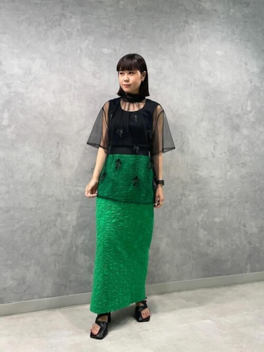ブラック系のTシャツ/カットソー、グリーン系のスカート、ブラック系のサンダルを着用したレディースの夏コーディネートの1枚目の写真