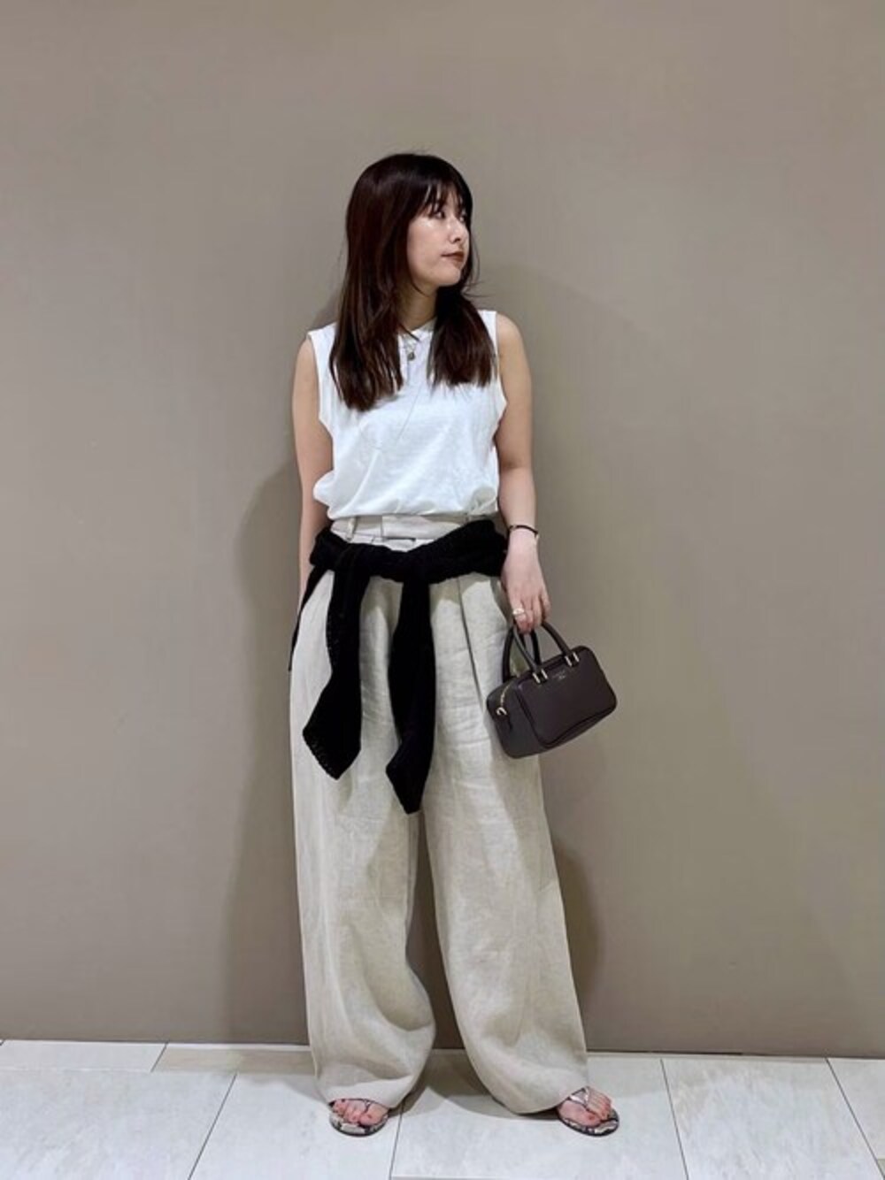 ベージュ系のその他パンツ、ホワイト系のタンクトップ、ブラウン系のニット/セーターを着用したレディースの春コーディネートの1枚目の写真
