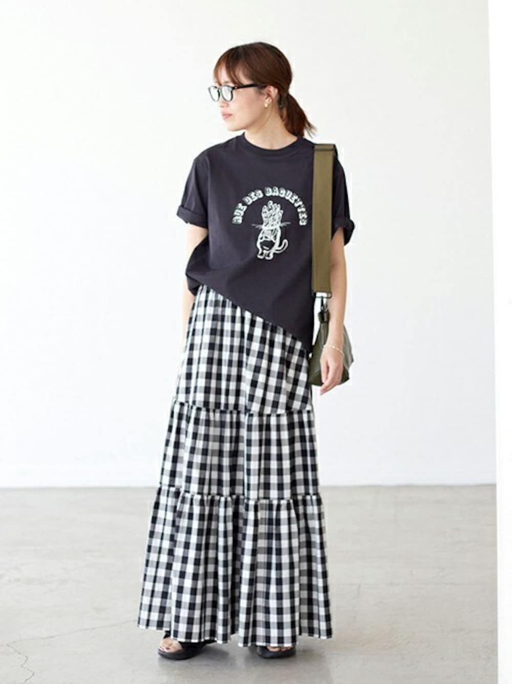 ホワイト系のスカート、グリーン系のショルダーバッグ、ブラック系のサンダルを着用したレディースの春コーディネートの1枚目の写真