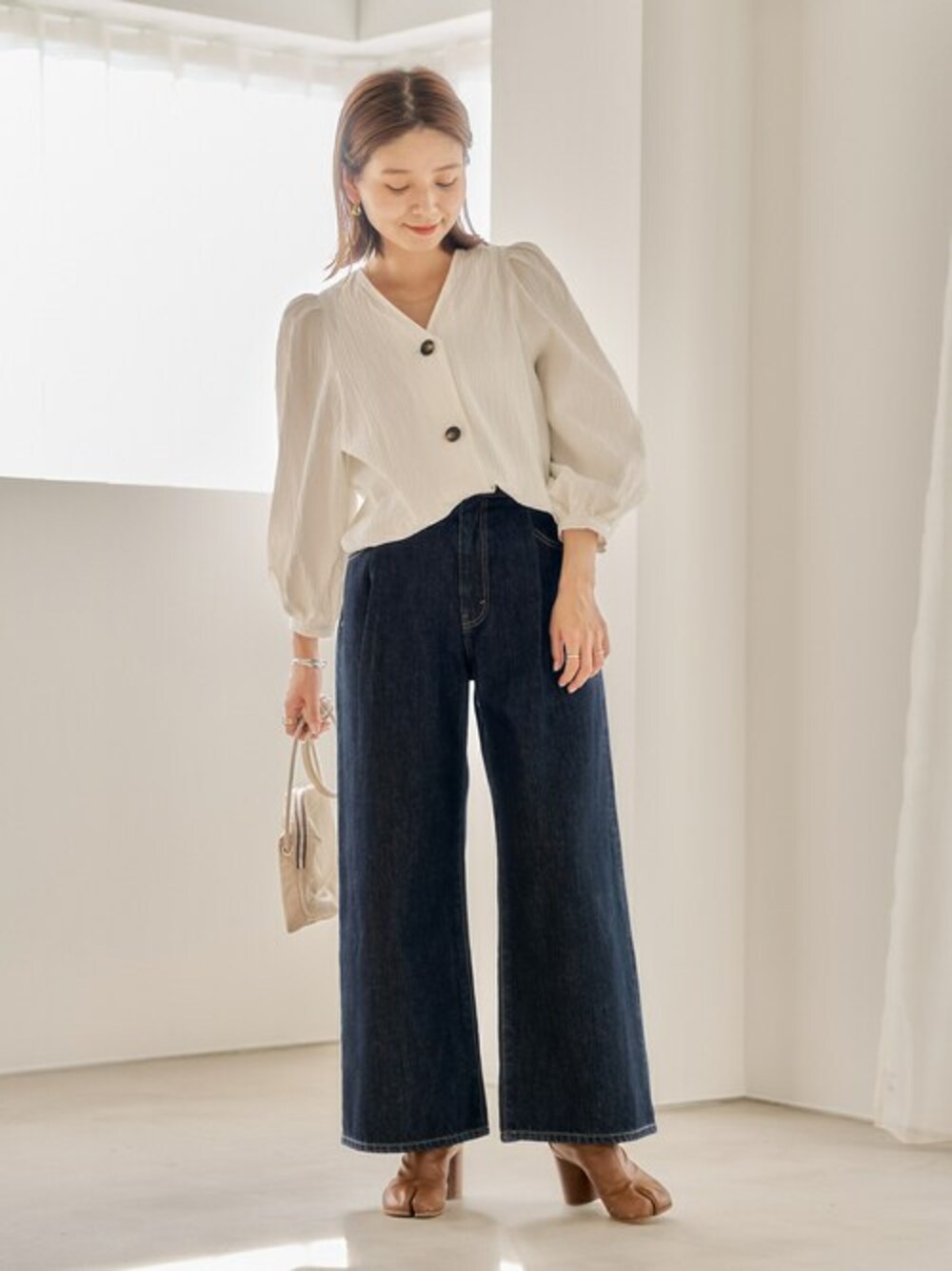 ホワイト系のシャツ/ブラウス、ブルー系のデニムパンツ、ベージュ系のショルダーバッグを着用したレディースの春コーディネートの1枚目の写真