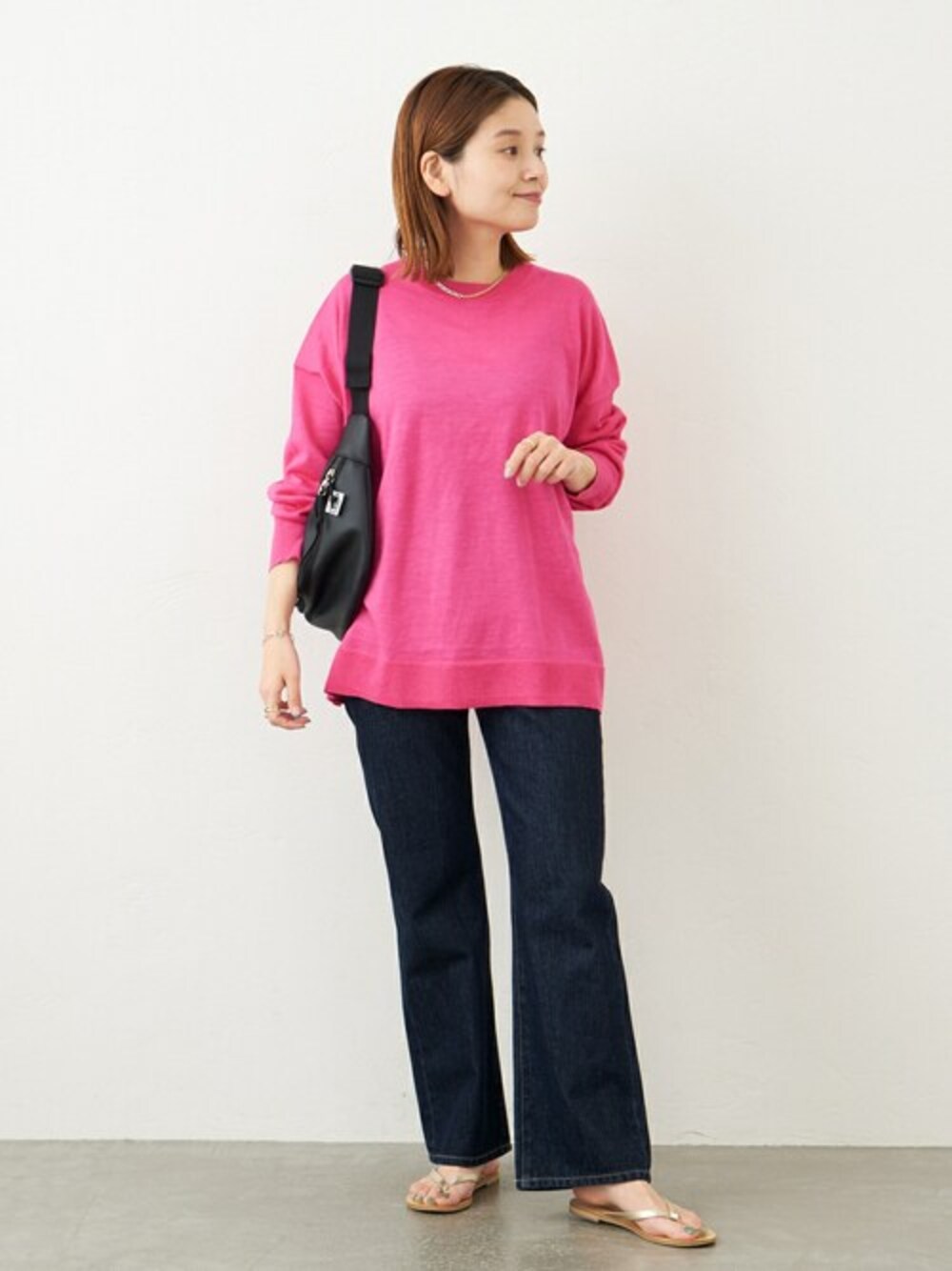 ピンク系のニット/セーター、ブルー系のデニムパンツ、ブラック系のショルダーバッグを着用したレディースの春コーディネートの1枚目の写真