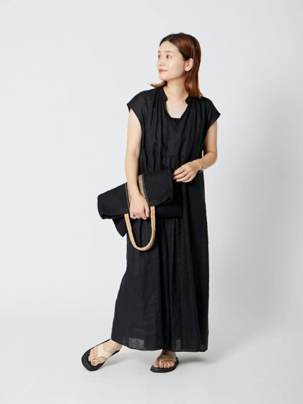 ブラック系のワンピース、ブラック系のトートバッグ、ベージュ系のサンダルを着用したレディースの夏コーディネートの1枚目の写真