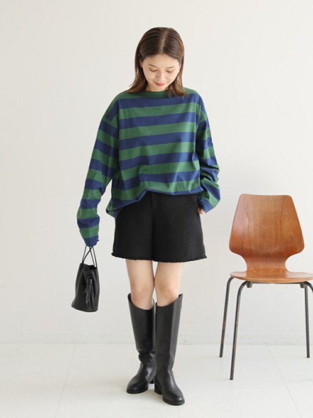 グリーン系のTシャツ/カットソー、ブラック系のブーツ、ブラック系のハンドバッグを着用したレディースの夏コーディネートの1枚目の写真