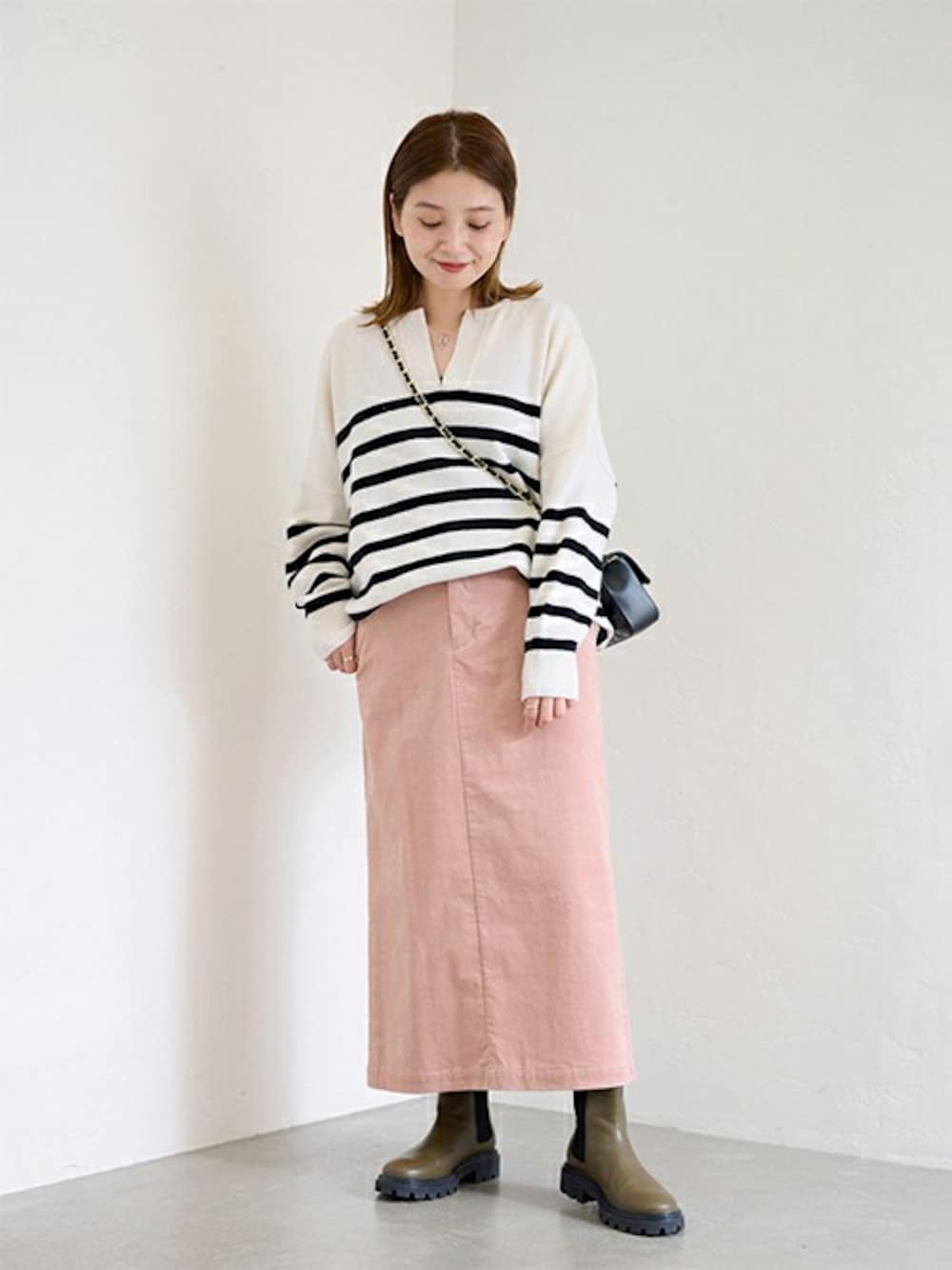 ホワイト系のニット/セーター、ピンク系のスカート、グリーン系のブーツを着用したレディースの秋コーディネートの1枚目の写真