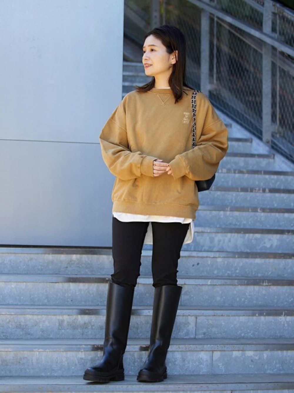 ベージュ系のスウェット、ブラック系のブーツ、ブラック系のショルダーバッグを着用したレディースの秋コーディネートの1枚目の写真