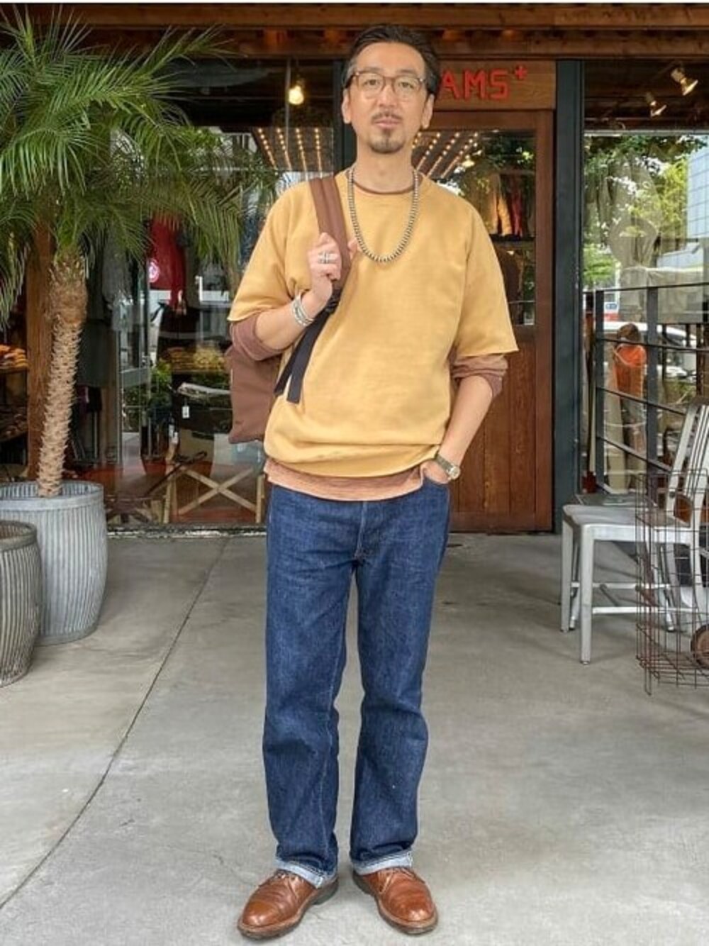 グリーン系のスウェット、ブラウン系のバックパック/リュックを着用したメンズの春コーディネートの1枚目の写真