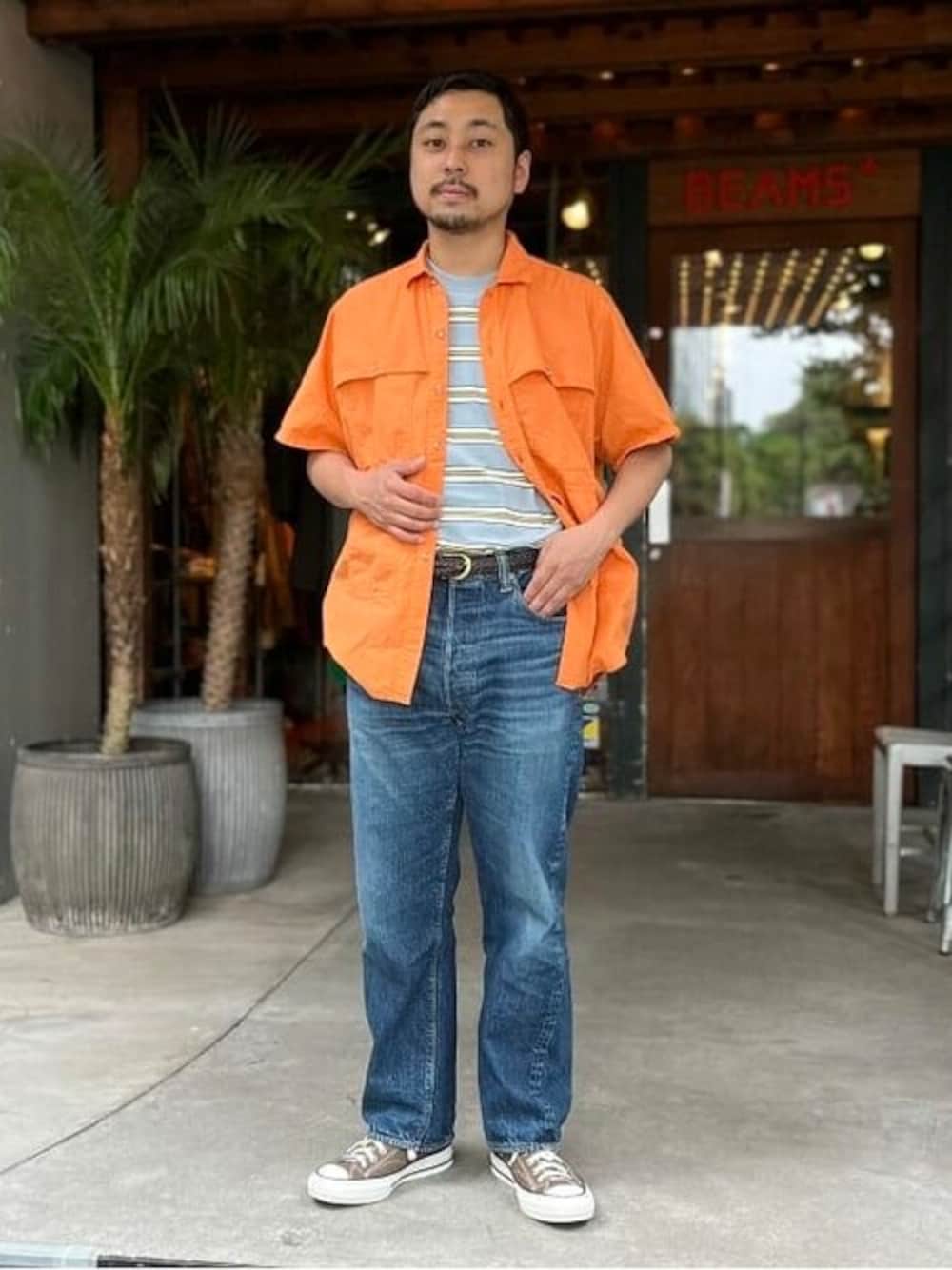 オレンジ系のシャツ/ブラウス、ブルー系のTシャツ/カットソー、ブラウン系のベルトを着用したメンズの春コーディネートの1枚目の写真