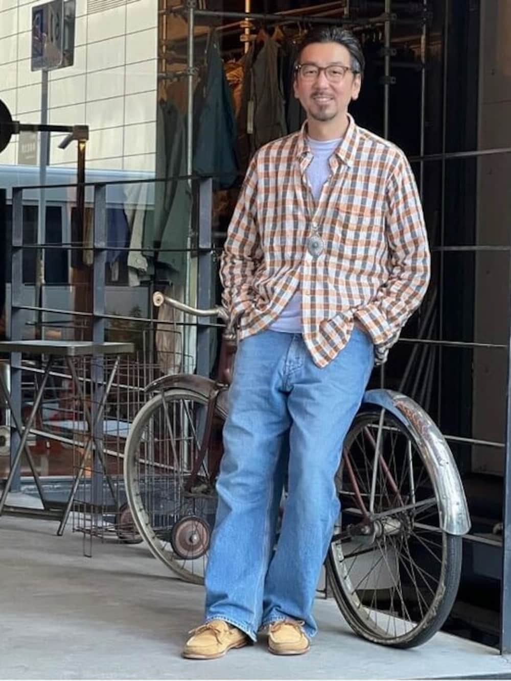 オレンジ系のシャツ/ブラウス、シルバー系のTシャツ/カットソー、ブルー系のデニムパンツを着用したメンズの春コーディネートの1枚目の写真