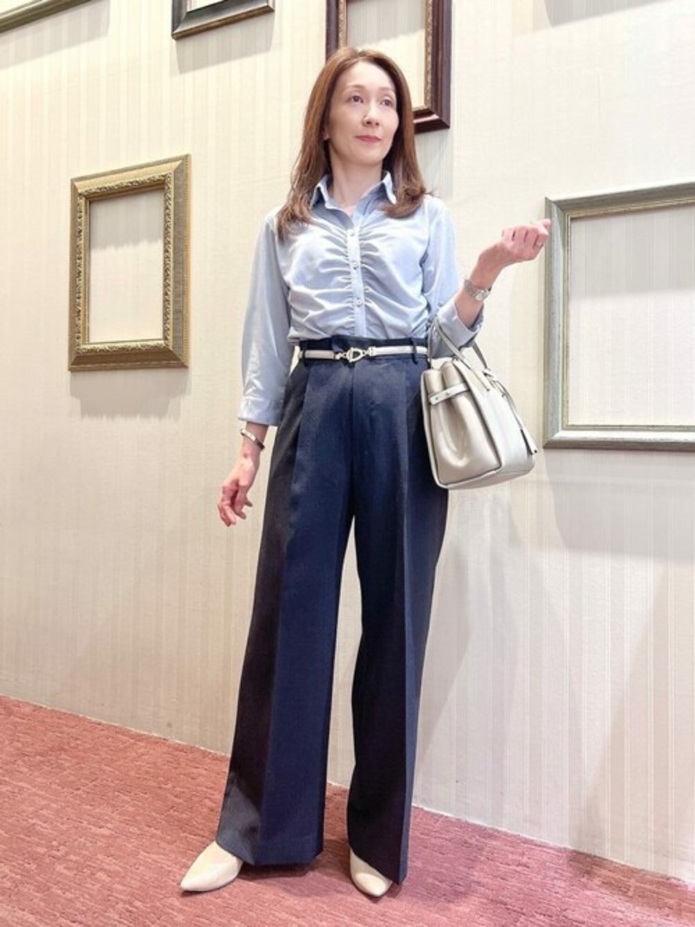 ブルー系のスーツパンツ、グレー系のハンドバッグ、ブルー系のビジネスシャツを着用したレディースの夏コーディネートの1枚目の写真