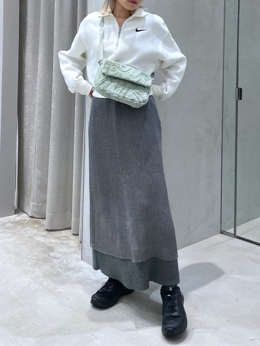 ブラック系のスニーカー、グレー系のスカート、グリーン系のショルダーバッグを着用したレディースの秋コーディネートの1枚目の写真