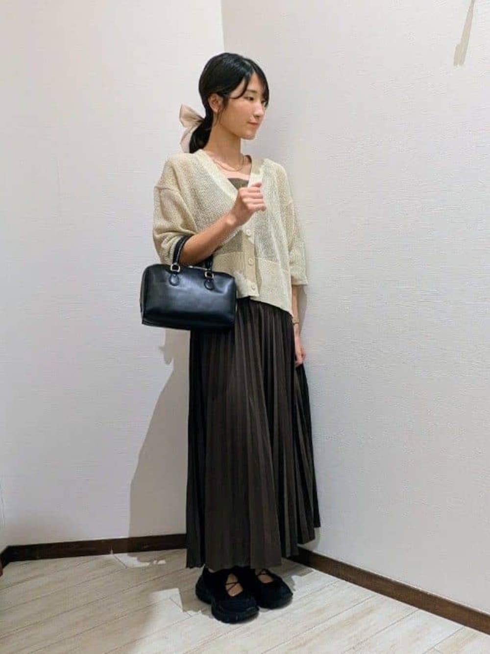ベージュ系のカーディガン/ボレロ、ブラウン系のスカート、ブラック系のスニーカーを着用したレディースの秋コーディネートの1枚目の写真