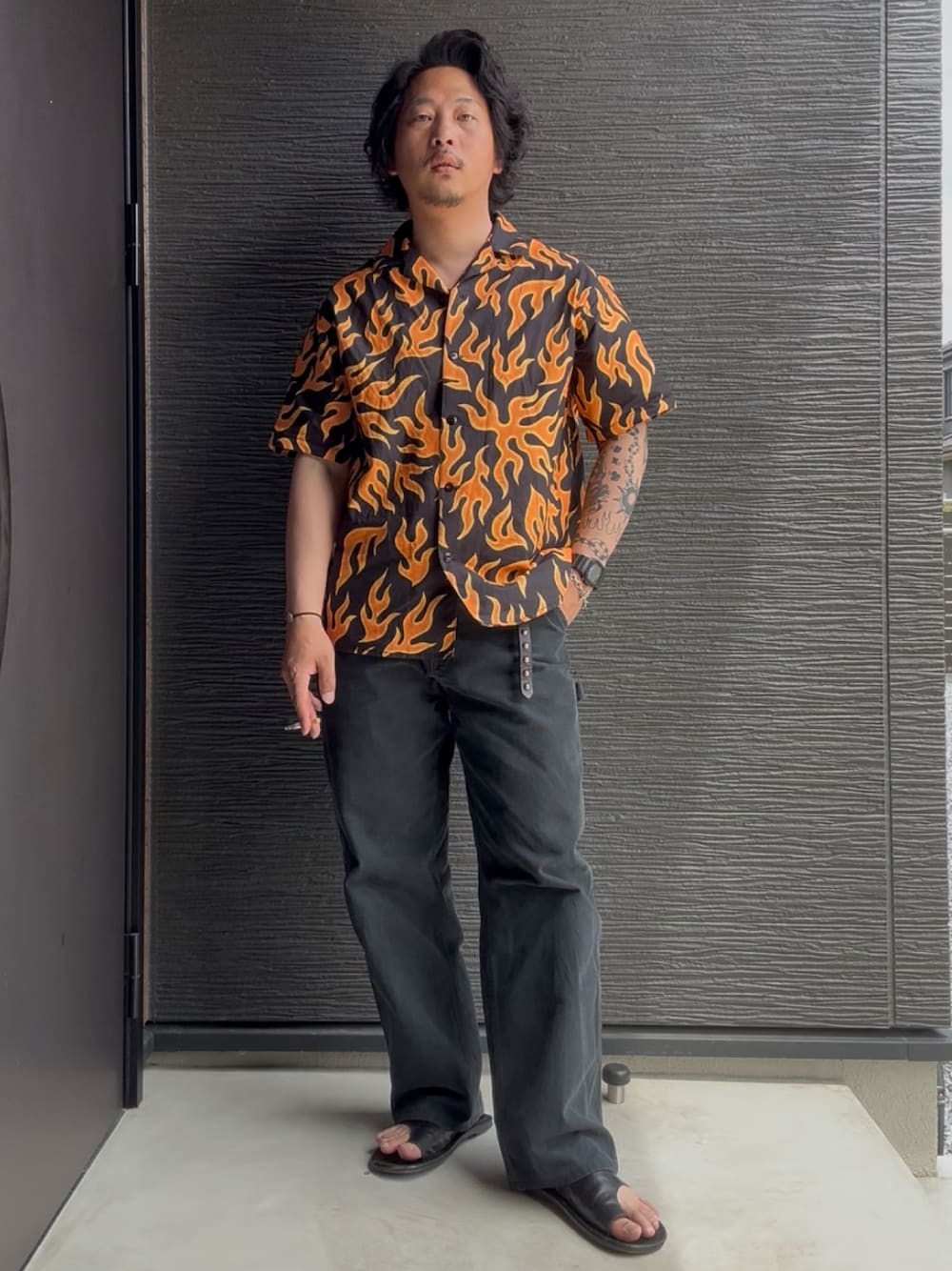 オレンジ系のTシャツ/カットソー、ブラック系のその他パンツ、ブラック系のサンダルを着用したメンズの夏コーディネートの1枚目の写真