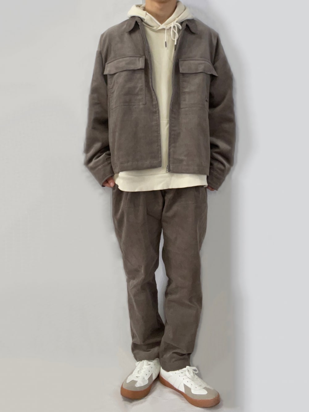 ベージュ系のセットアップ、ベージュ系のパーカー、ホワイト系のスニーカーを着用したメンズの秋コーディネートの1枚目の写真