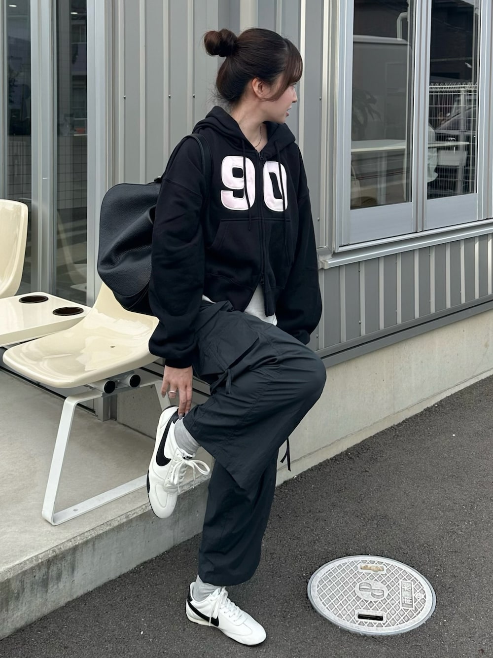 ブラック系のパーカー、ホワイト系のスニーカー、グレー系のカーゴパンツを着用したレディースの秋コーディネートの1枚目の写真