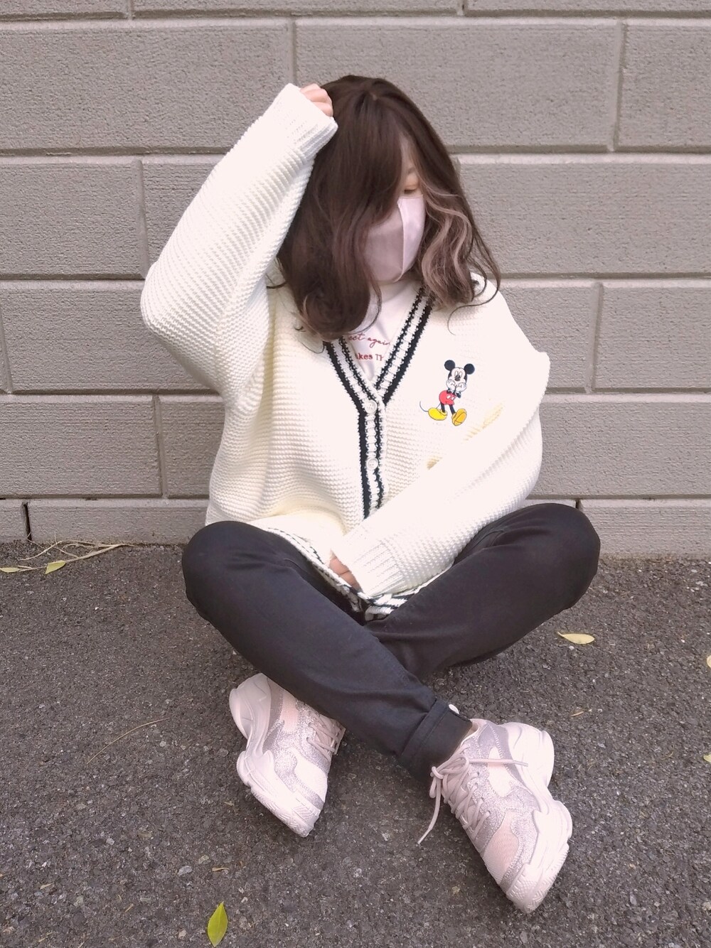 ピンク系のスニーカー、ブラック系のデニムパンツ、ホワイト系のカーディガン/ボレロを着用したレディースの冬コーディネートの1枚目の写真