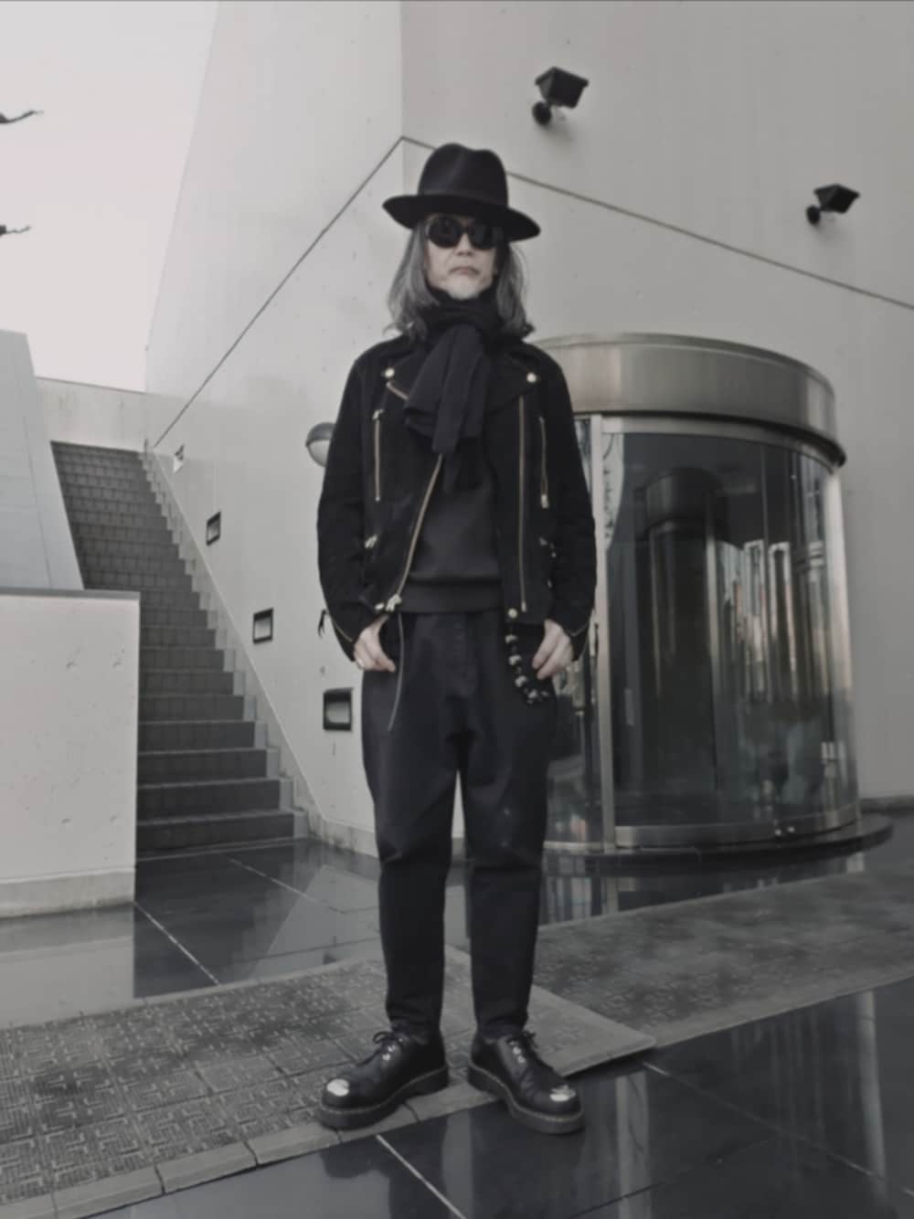 ブラック系のデニムパンツ、ブラック系のドレスシューズ、ブラック系のライダースジャケットを着用したメンズの冬コーディネートの1枚目の写真