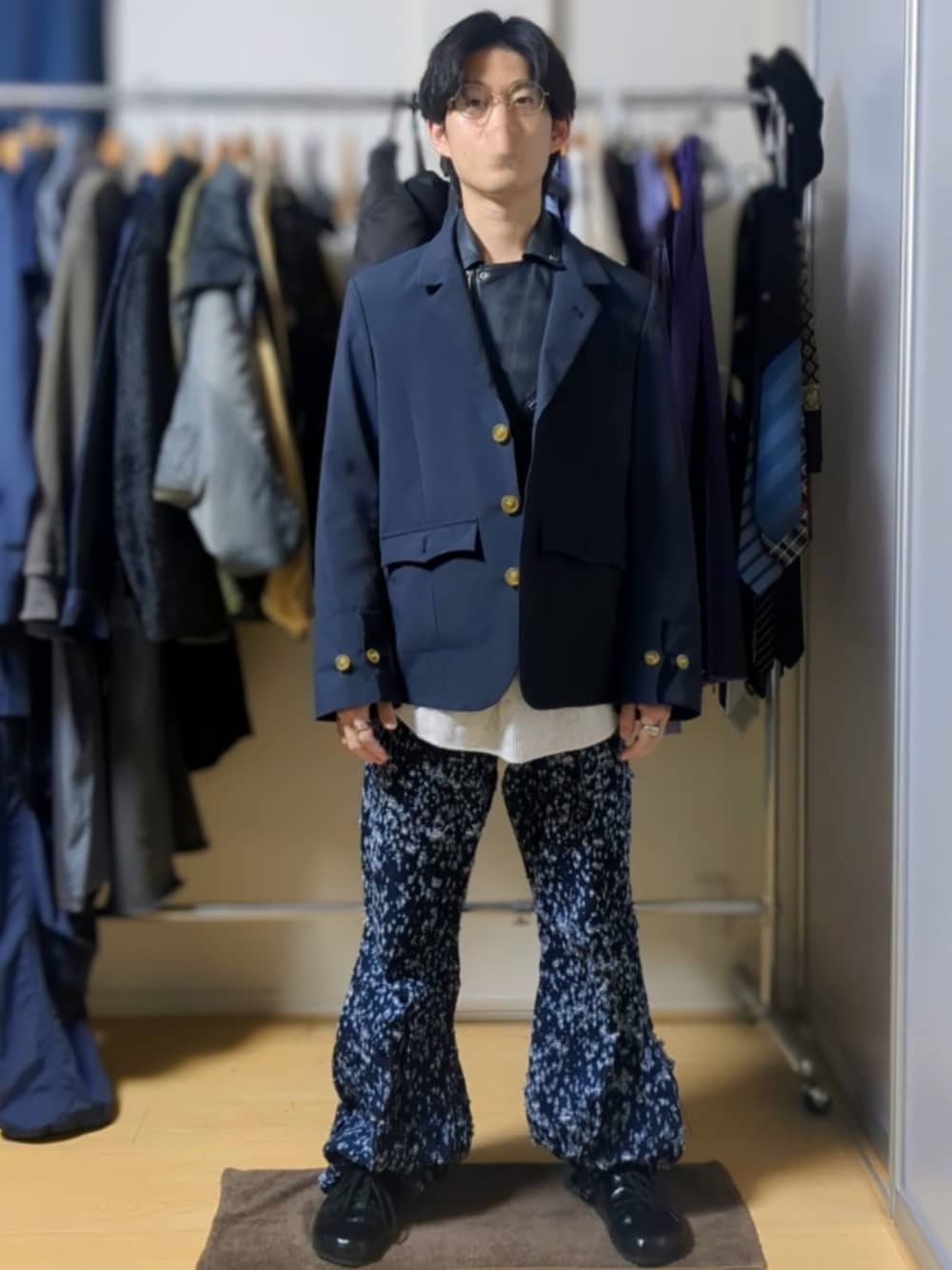 ブルー系のデニムパンツ、ブラック系のスリッポン、グリーン系のメガネを着用したメンズの秋コーディネートの1枚目の写真