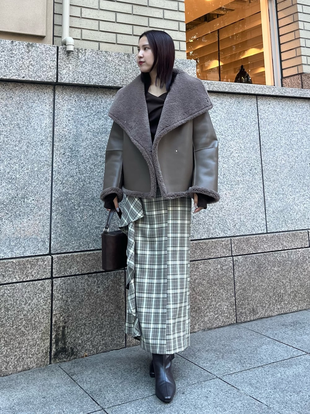 ベージュ系のムートンコート、ブラウン系のTシャツ/カットソー、ブラウン系のスカートを着用したレディースの冬コーディネートの1枚目の写真
