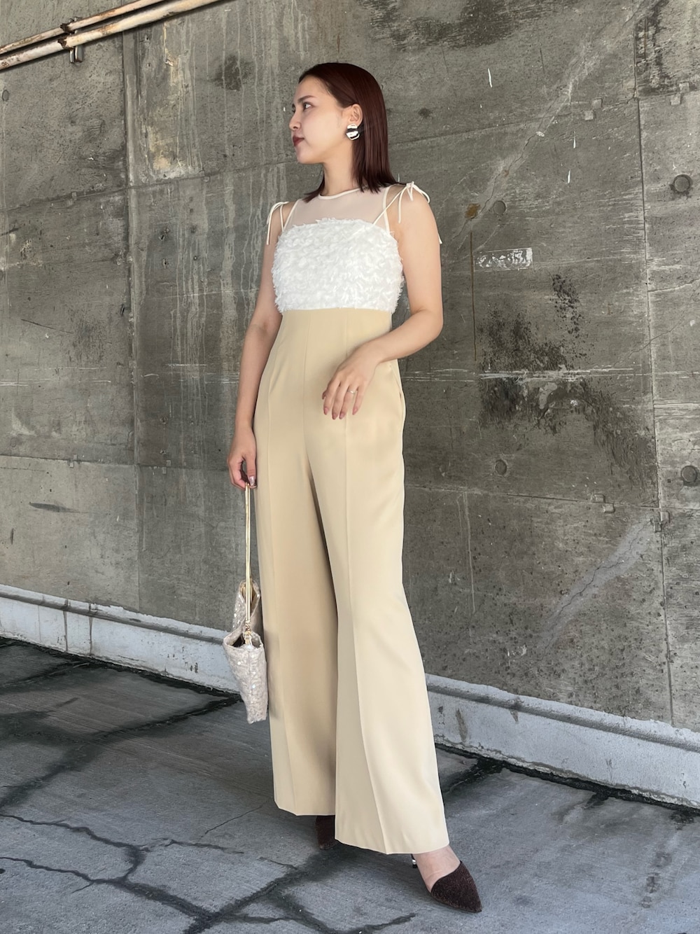 ベージュ系のショルダーバッグ、その他のパンプス、ベージュ系のパンツドレスを着用したレディースの春コーディネートの1枚目の写真