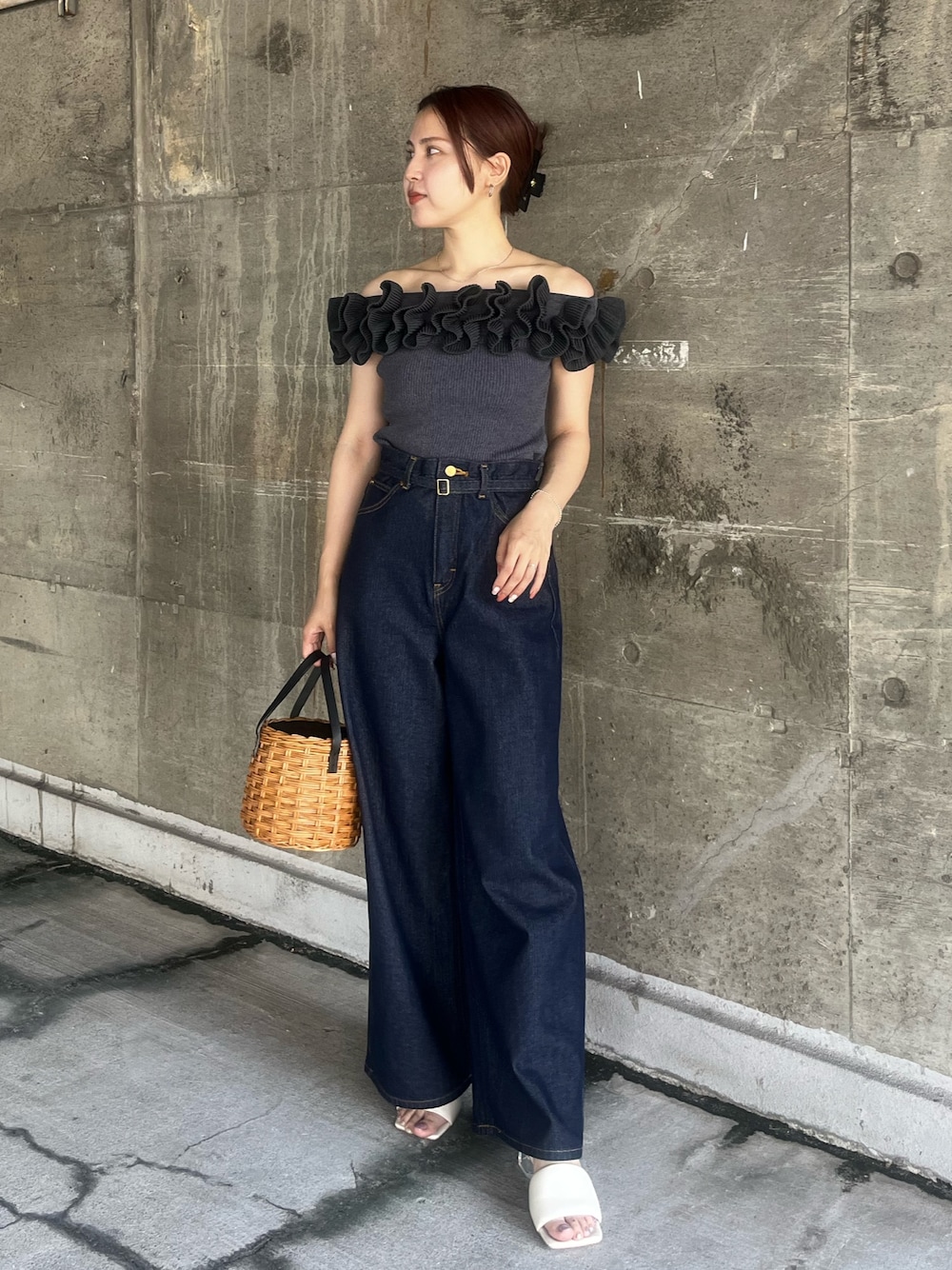 グレー系のニット/セーター、ブラウン系のハンドバッグ、ブルー系のデニムパンツを着用したレディースの夏コーディネートの1枚目の写真