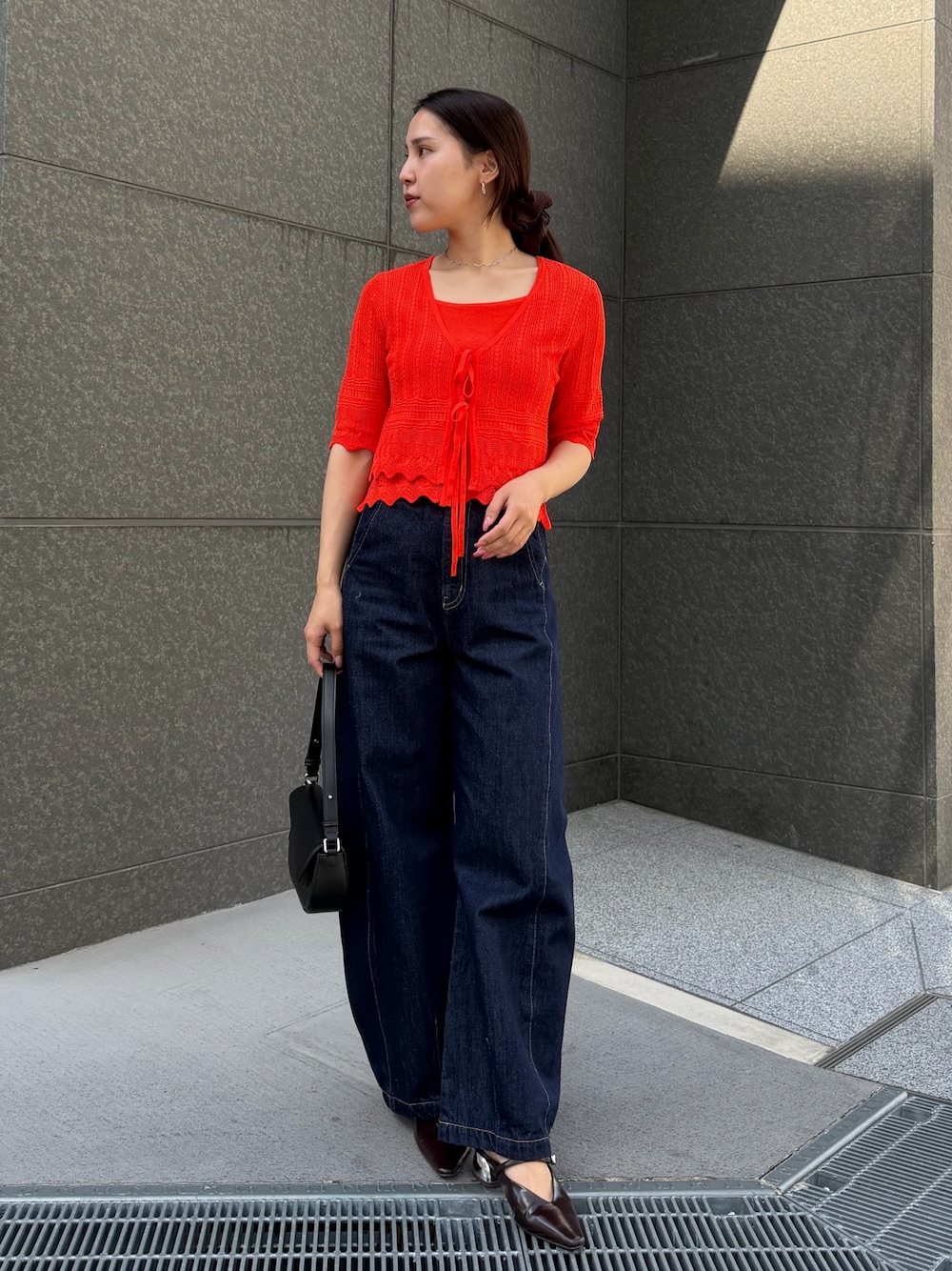 ブルー系のデニムパンツ、オレンジ系のアンサンブルを着用したレディースの春コーディネートの1枚目の写真