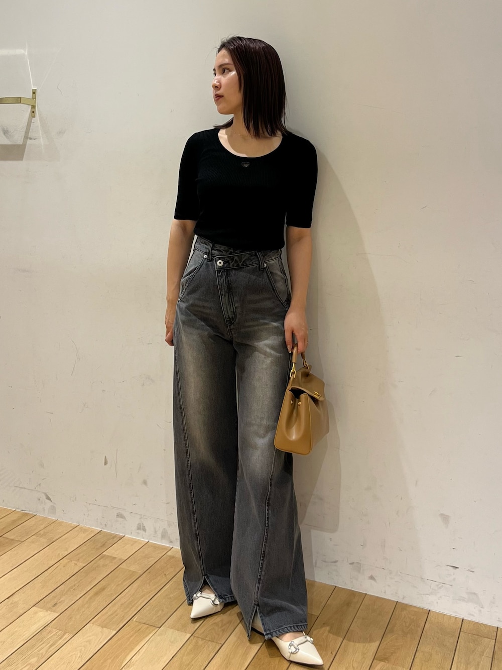 ブラック系のニット/セーター、ブラック系のデニムパンツ、ブラウン系のハンドバッグを着用したレディースの春コーディネートの1枚目の写真