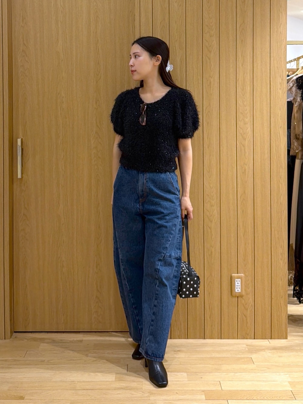 ブルー系のデニムパンツ、ブラック系のニット/セーター、ブラック系のハンドバッグを着用したレディースの秋コーディネートの1枚目の写真