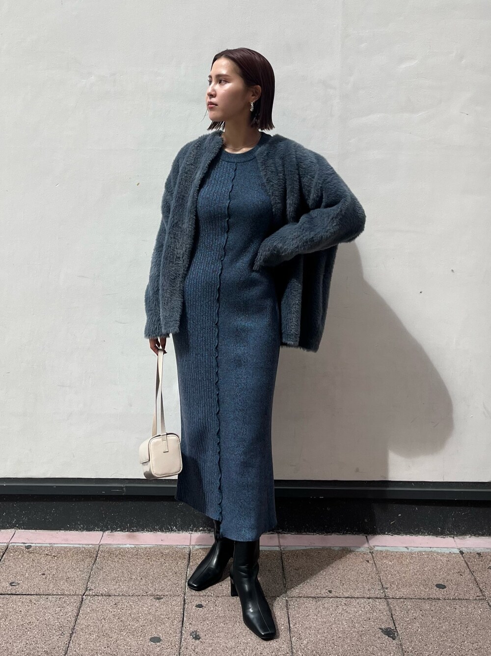 ブラック系のブーツ、ホワイト系のショルダーバッグ、ブルー系のワンピースを着用したレディースの秋コーディネートの1枚目の写真