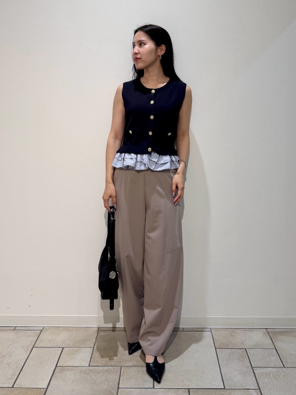 ベージュ系のその他パンツ、ブルー系のニット/セーター、ブラック系のハンドバッグを着用したレディースの夏コーディネートの1枚目の写真