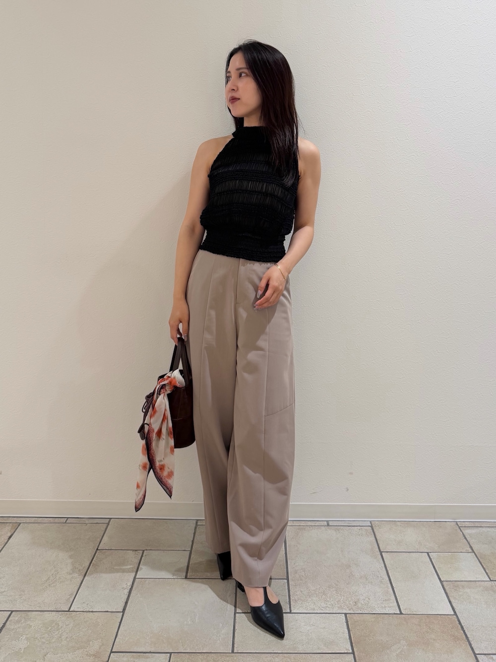 ブラウン系のハンドバッグ、ベージュ系のその他パンツ、ブラック系のシャツ/ブラウスを着用したレディースの夏コーディネートの1枚目の写真