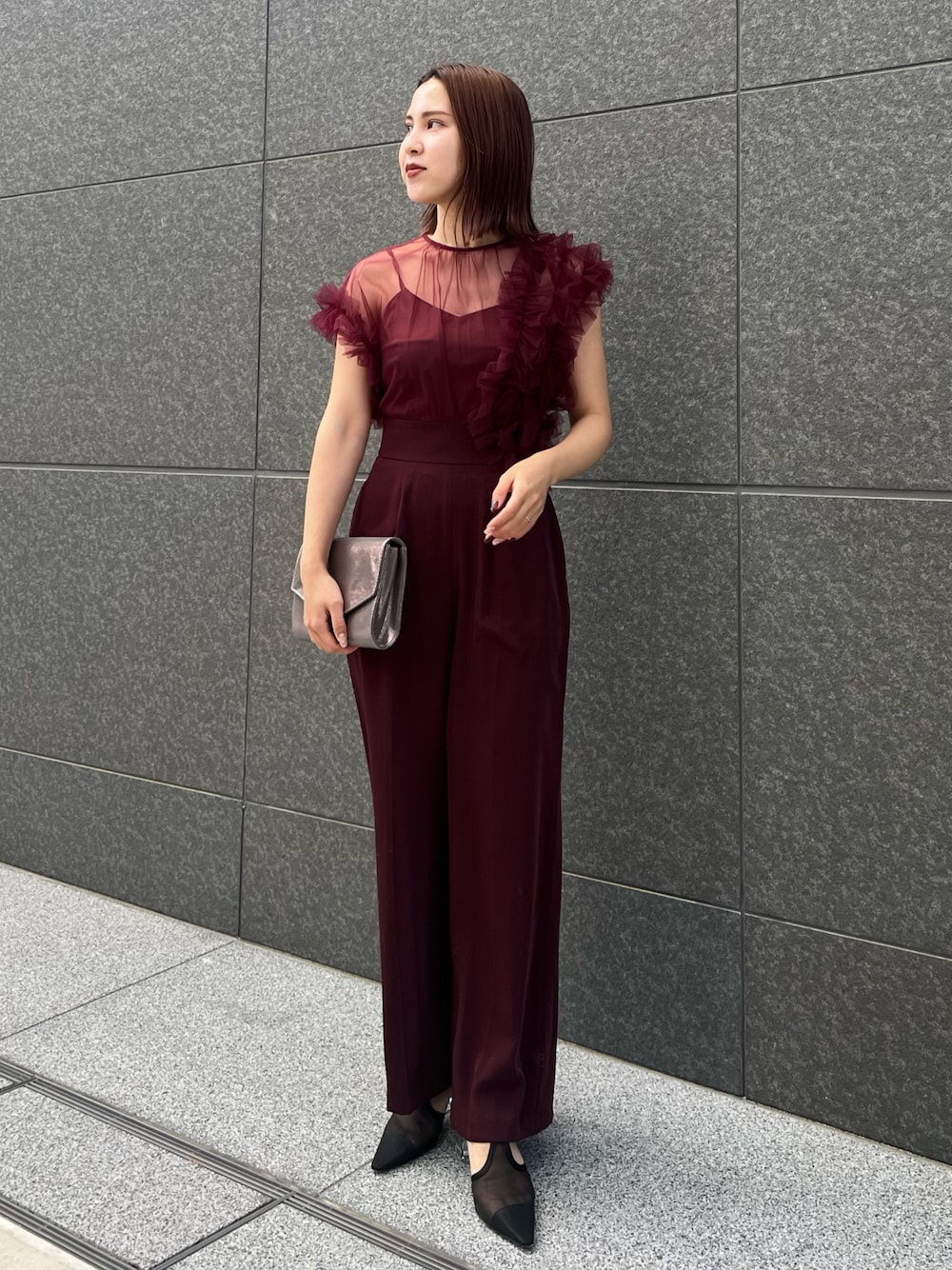 シルバー系のハンドバッグ、レッド系のパンツドレスを着用したレディースの冬コーディネートの1枚目の写真