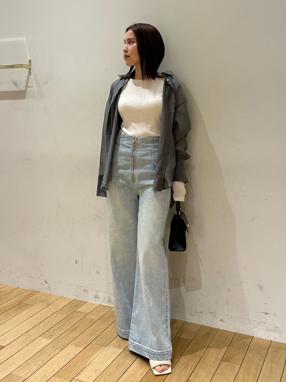 ホワイト系のサンダル、ブラック系のハンドバッグ、ブルー系のデニムパンツを着用したレディースの春コーディネートの1枚目の写真