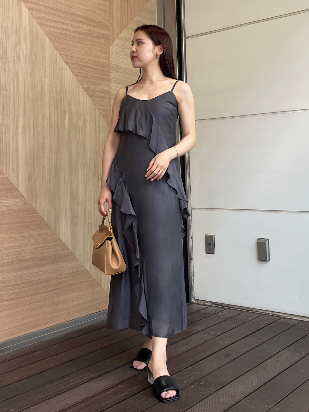 グレー系のワンピース、ブラウン系のハンドバッグ、ブラック系のサンダルを着用したレディースの夏コーディネートの1枚目の写真