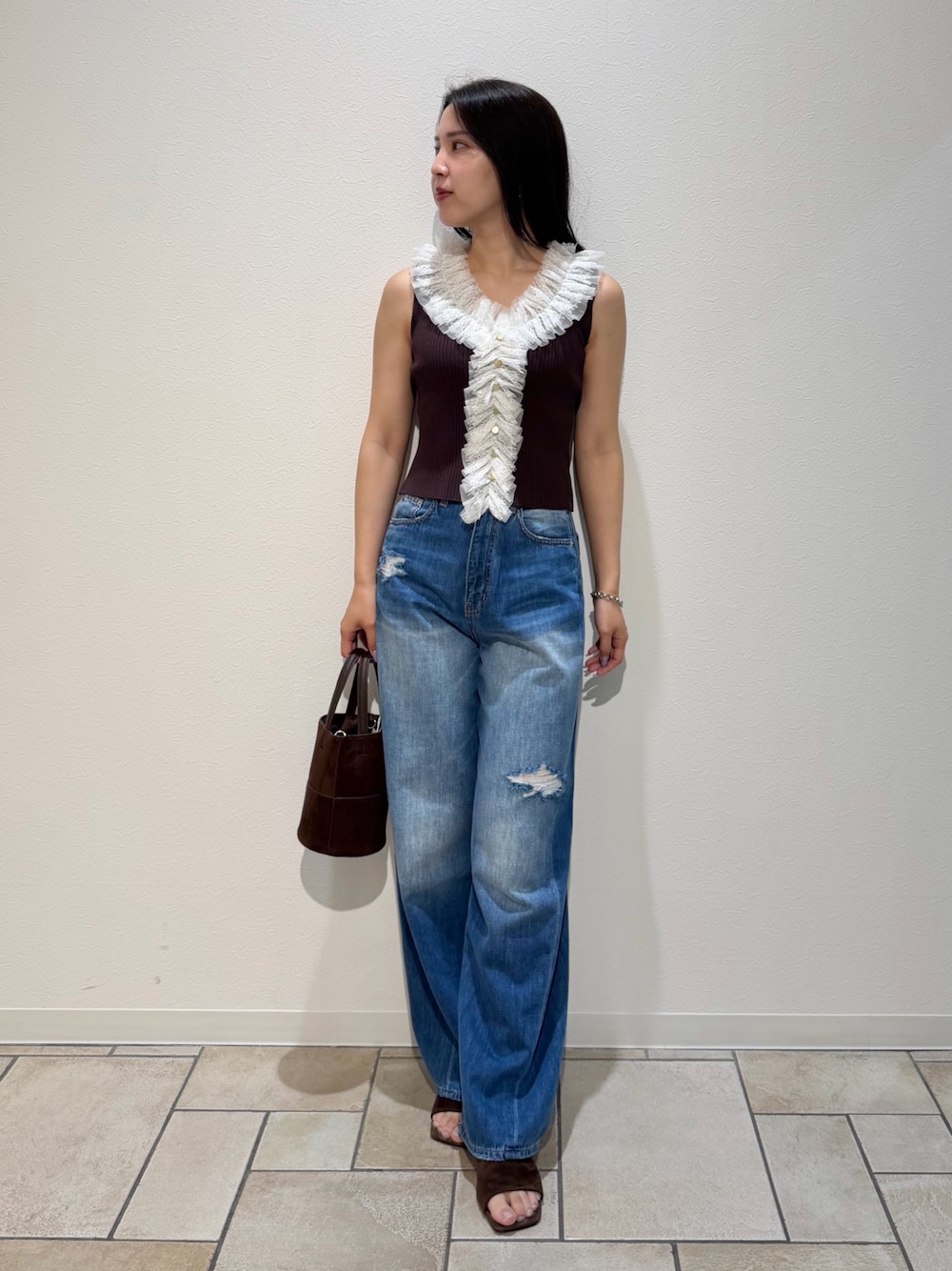 ブルー系のデニムパンツ、ブラウン系のサンダル、ブラウン系のハンドバッグを着用したレディースの夏コーディネートの1枚目の写真