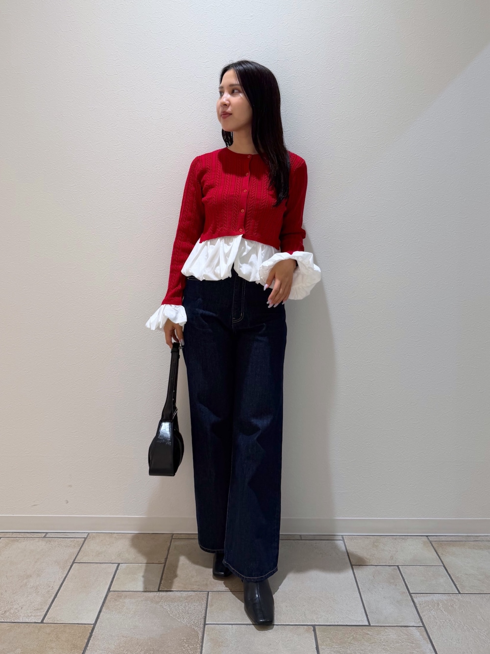レッド系のカーディガン/ボレロ、ブルー系のデニムパンツ、ブラック系のブーツを着用したレディースの秋コーディネートの1枚目の写真