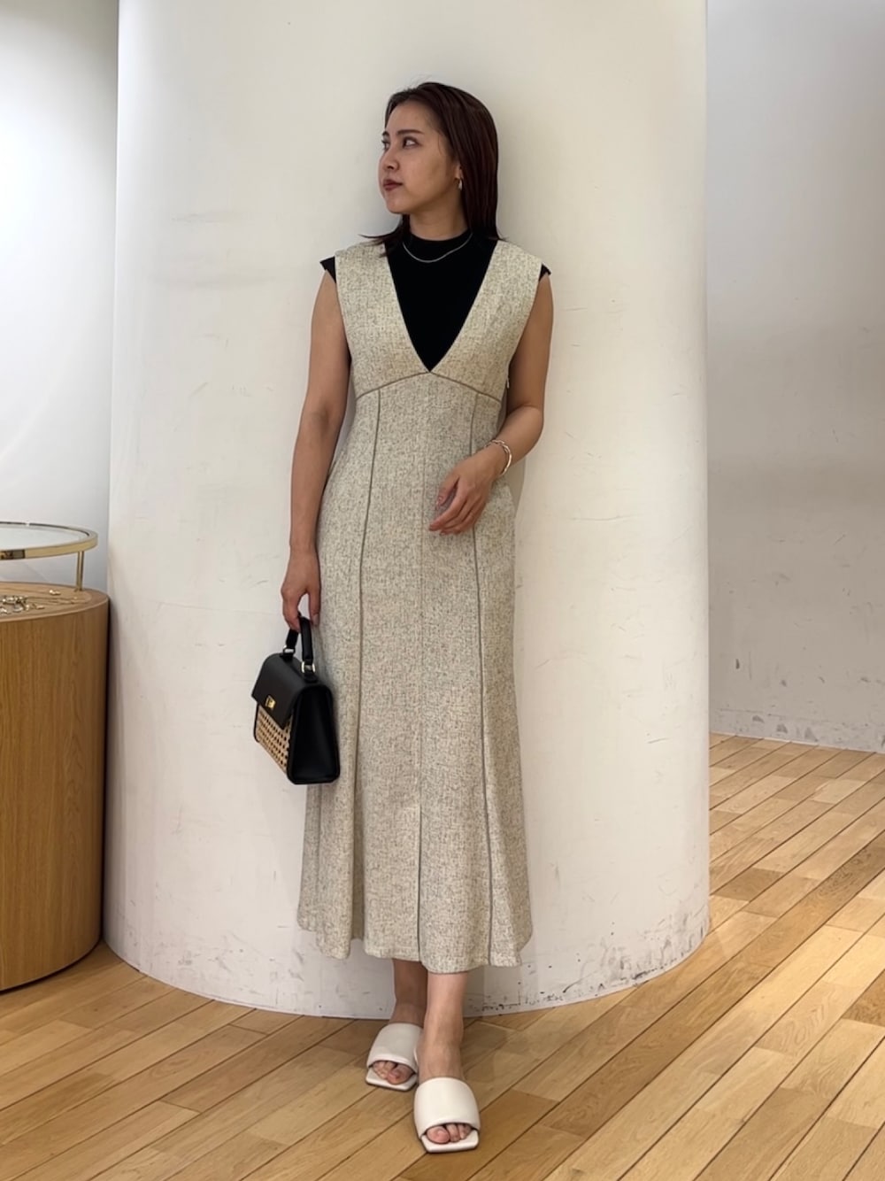 ブラック系のニット/セーター、ホワイト系のジャンパースカート、ブラック系のハンドバッグを着用したレディースの夏コーディネートの1枚目の写真
