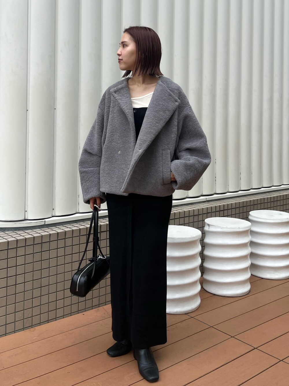 グレー系のブルゾン、ホワイト系のTシャツ/カットソー、ブラック系のショルダーバッグを着用したレディースの秋コーディネートの1枚目の写真