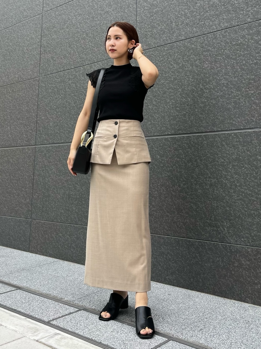 ブラック系のサンダル、ブラック系のニット/セーター、ベージュ系のスカートを着用したレディースの春コーディネートの1枚目の写真