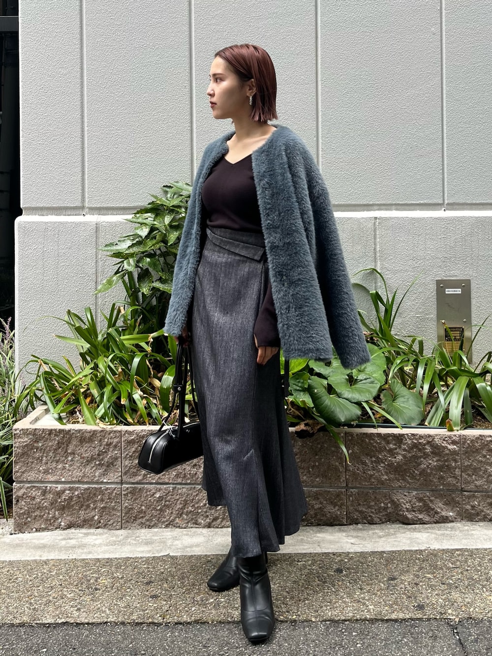 ブラック系のニット/セーター、グレー系のカーディガン/ボレロ、グレー系のスカートを着用したレディースの秋コーディネートの1枚目の写真