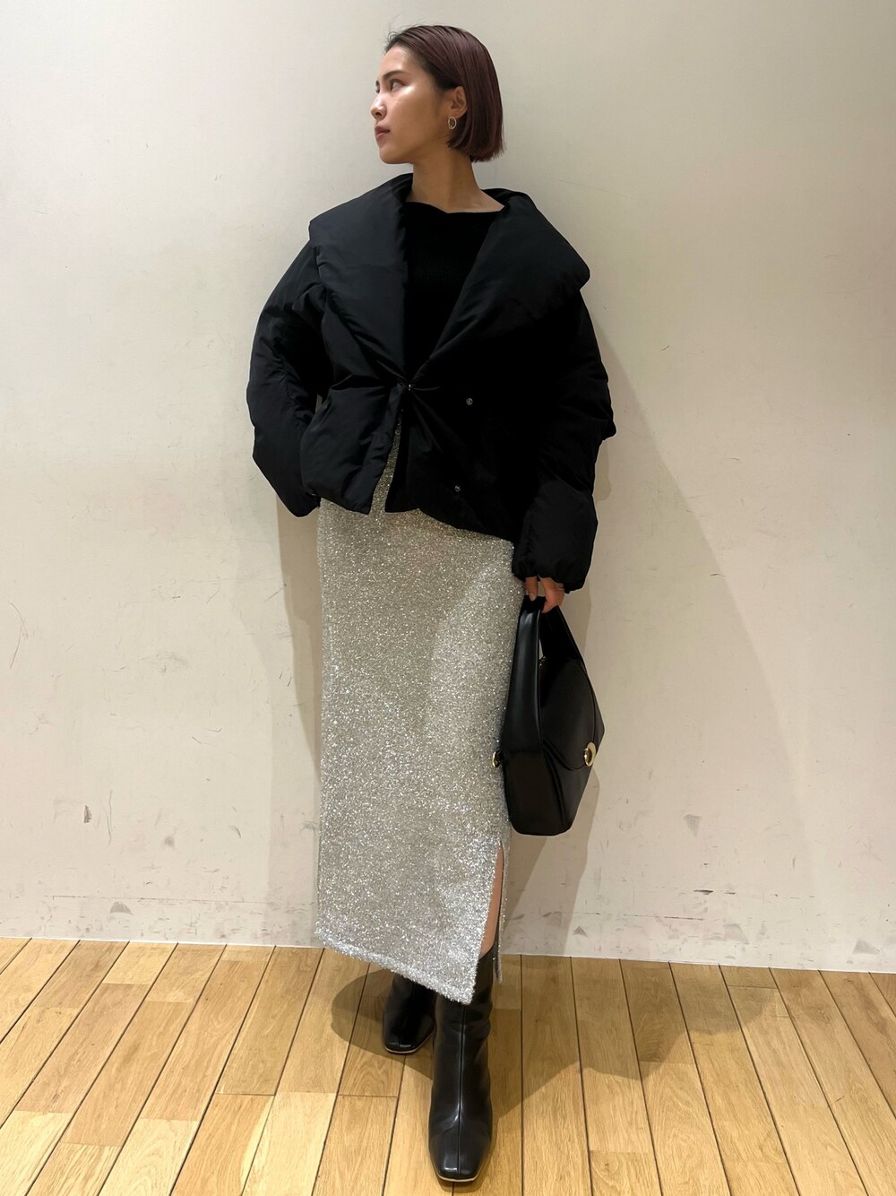 ブラック系のブーツ、ブラック系のハンドバッグ、シルバー系のスカートを着用したレディースの冬コーディネートの1枚目の写真