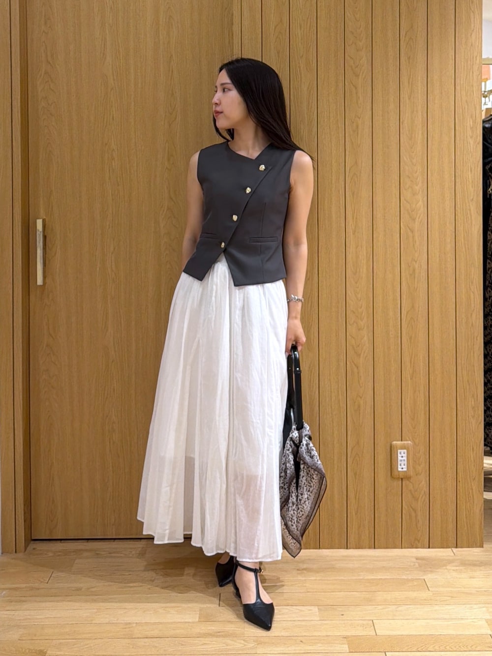 ブラック系のパンプス、グレー系のワンピース、ブラック系のハンドバッグを着用したレディースの夏コーディネートの1枚目の写真