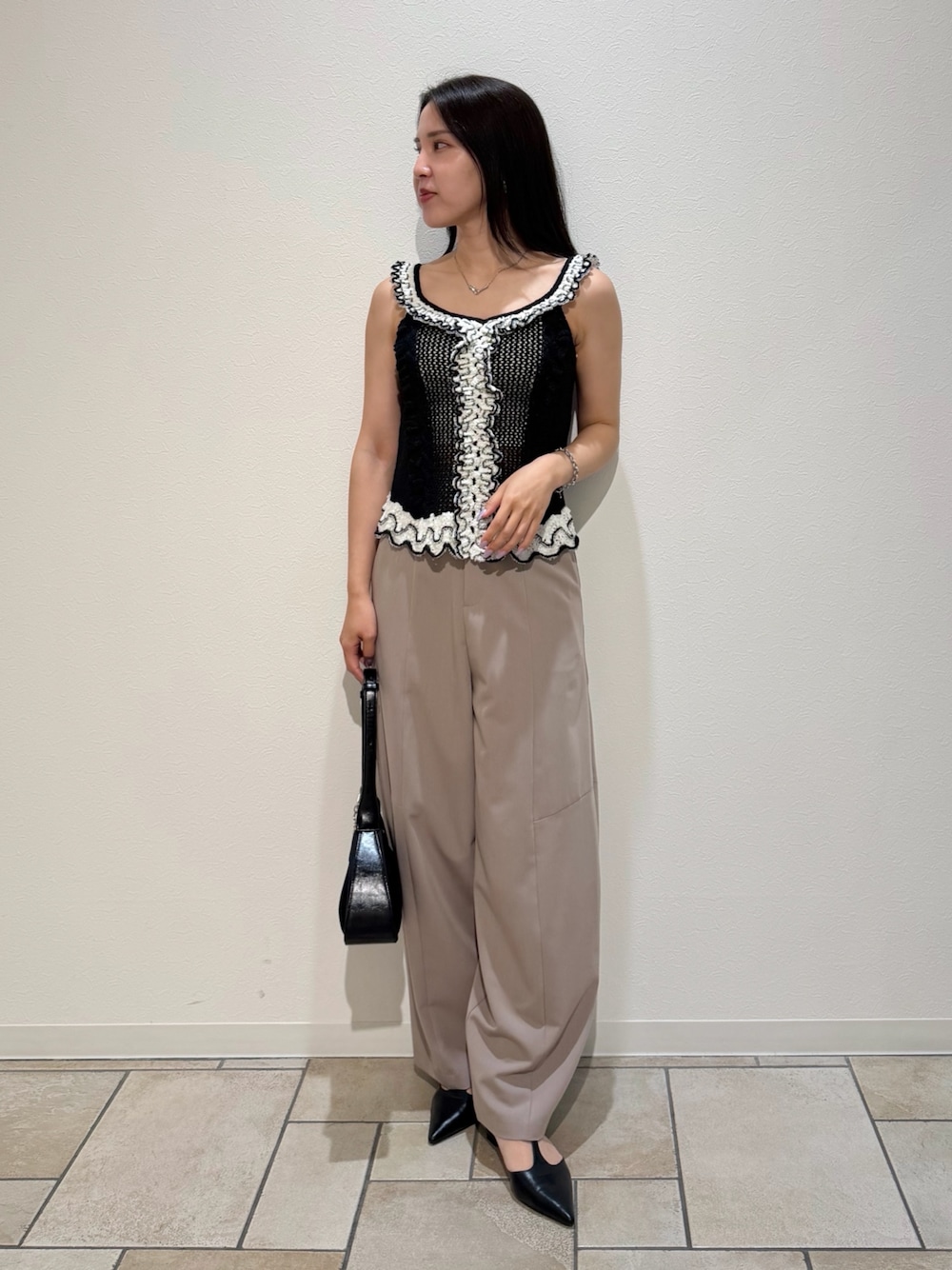 ベージュ系のその他パンツ、ブラック系のニット/セーター、ブラック系のハンドバッグを着用したレディースの夏コーディネートの1枚目の写真